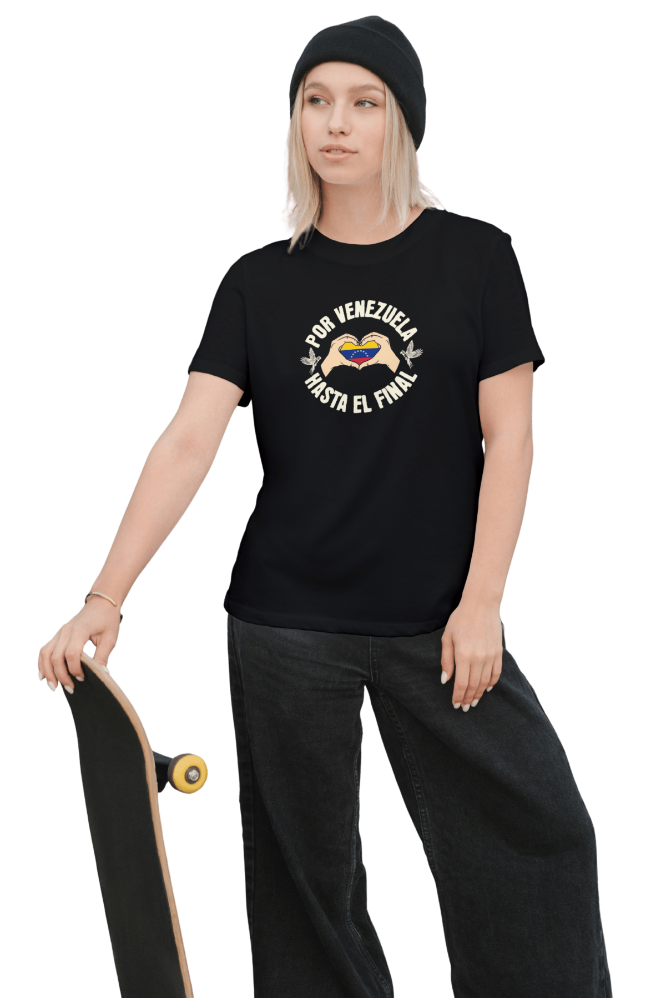 A blonde woman is wearing a black unisex t-shirt featuring a Venezuelan flag inside heart-shaped hands, the text "Por Venezuela Hasta El Final", and a pair of macaws on either side. She's holding a skateboard.