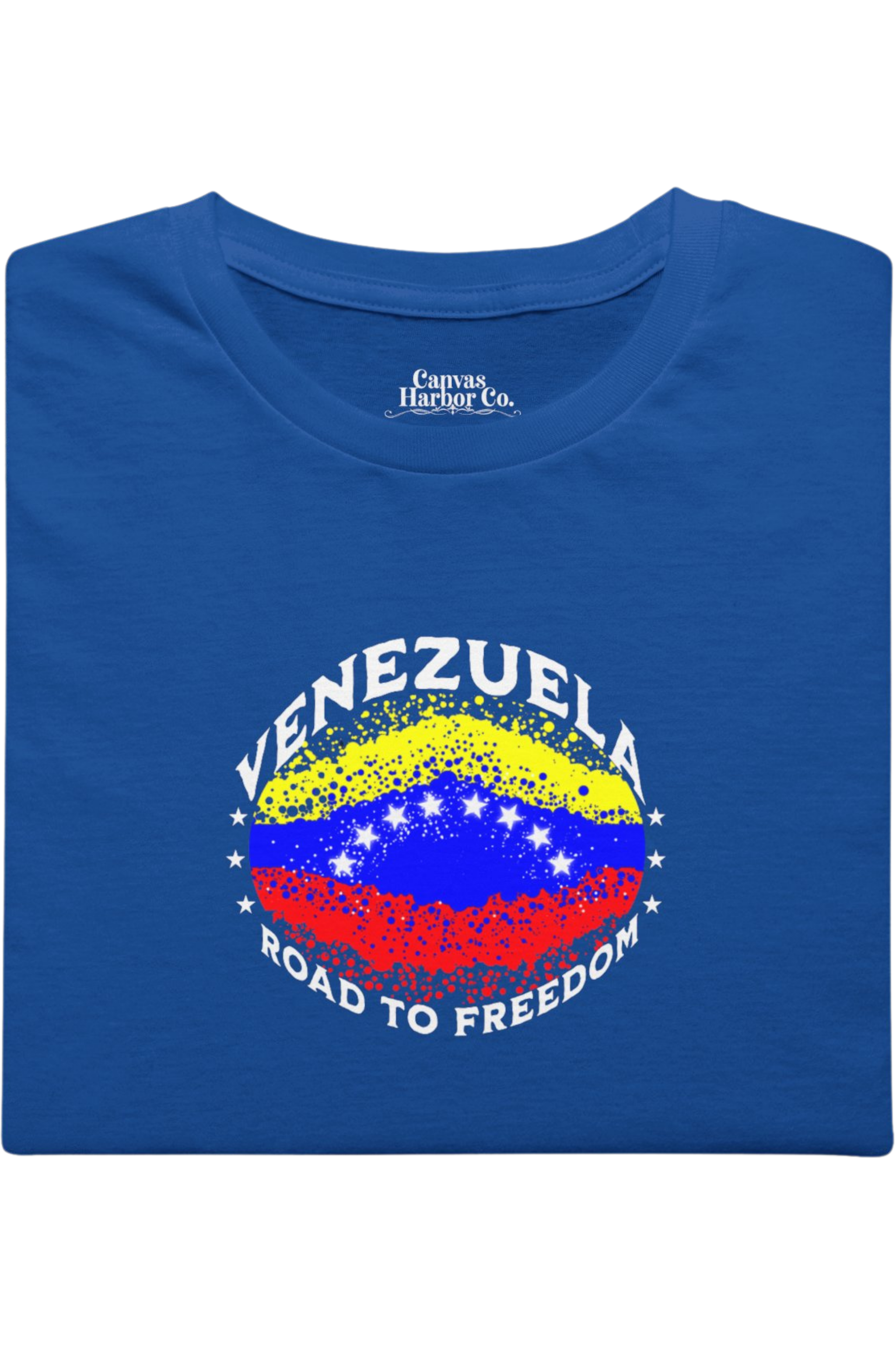 Blue folded T-shirt featuring an elliptical Venezuelan flag dotted with dots (like an explosion), with the word "VENEZUELA” at the top, the text “ROAD TO FREEDOM” below the flag, and 3 stars on each side.