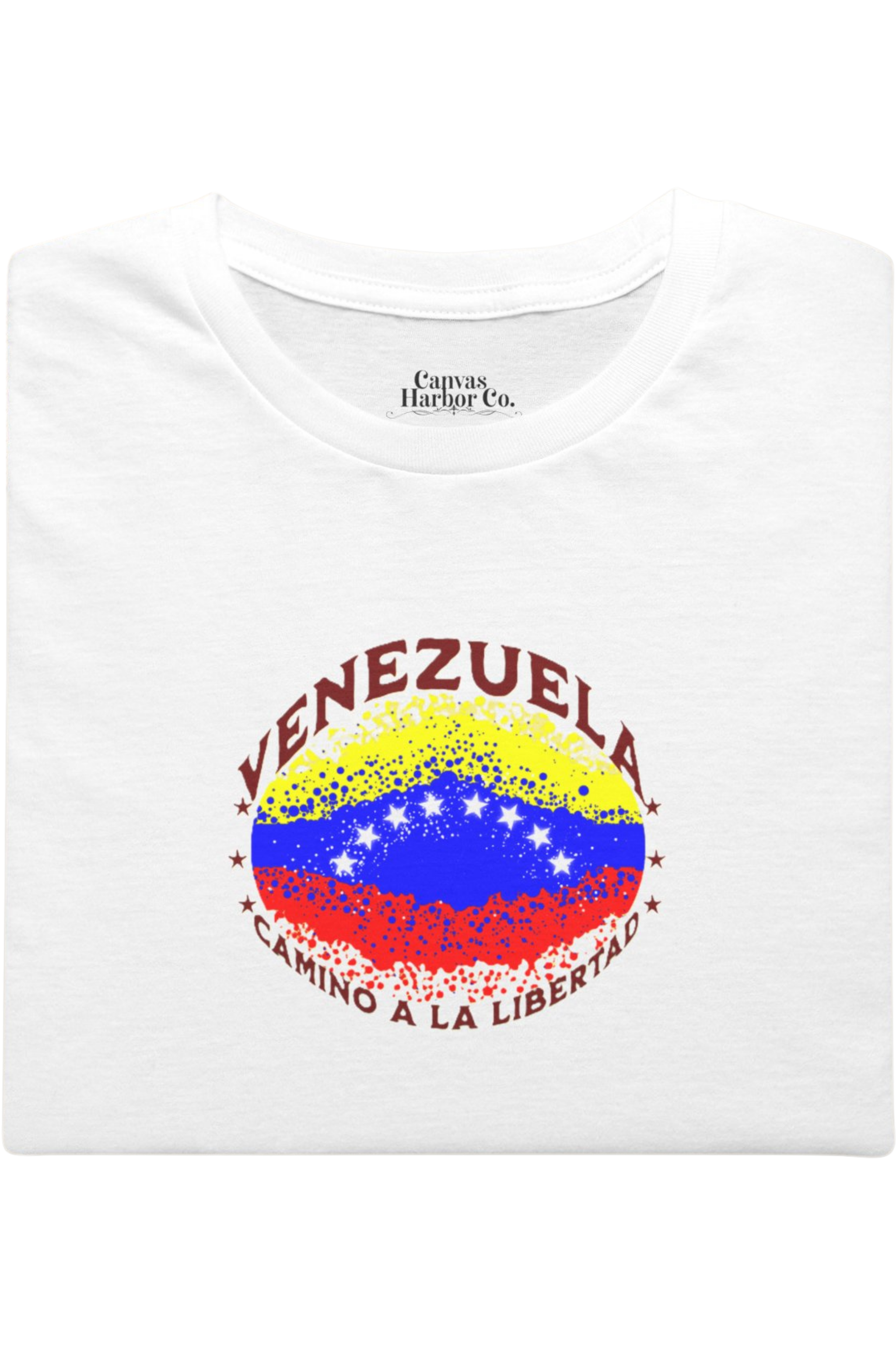 Franela blanca, doblada, con una bandera venezolana de forma elíptica salpicada de puntos (como una explosión), con el nombre "VENEZUELA” arriba, el texto “CAMINO A LA LIBERTAD" abajo y 3 estrellas en cada lado.