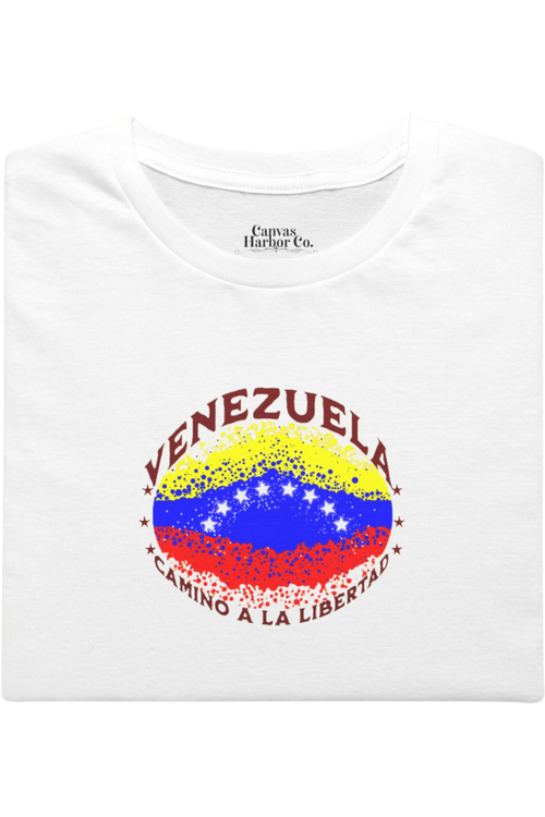 Franela blanca, doblada, con una bandera venezolana de forma elíptica salpicada de puntos (como una explosión), con el nombre "VENEZUELA” arriba, el texto “CAMINO A LA LIBERTAD" abajo y 3 estrellas en cada lado.