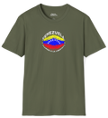 Franela color verde oliva con una bandera venezolana de forma elíptica salpicada de puntos (como una explosión), con el nombre "VENEZUELA” arriba, el texto “CAMINO A LA LIBERTAD" abajo y 3 estrellas en cada lado.