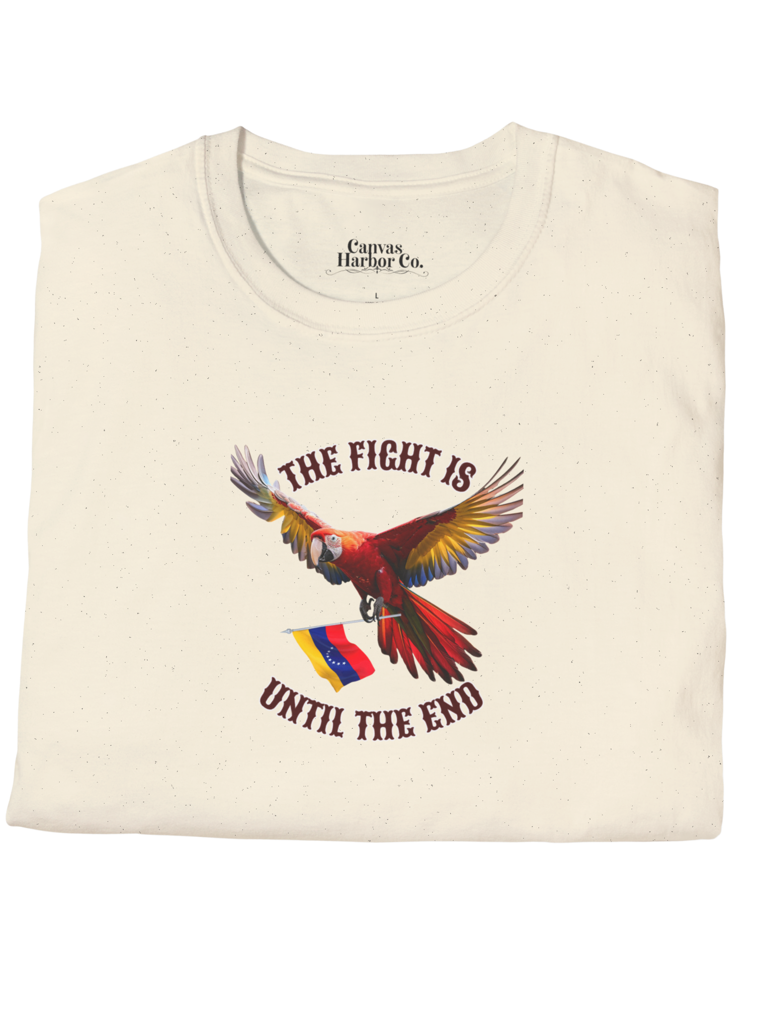 Pale orange folded T-shirt featuring an image of a macaw and the Venezuelan flag. The text "THE FIGHT IS UNTIL THE END" surrounds the bird.