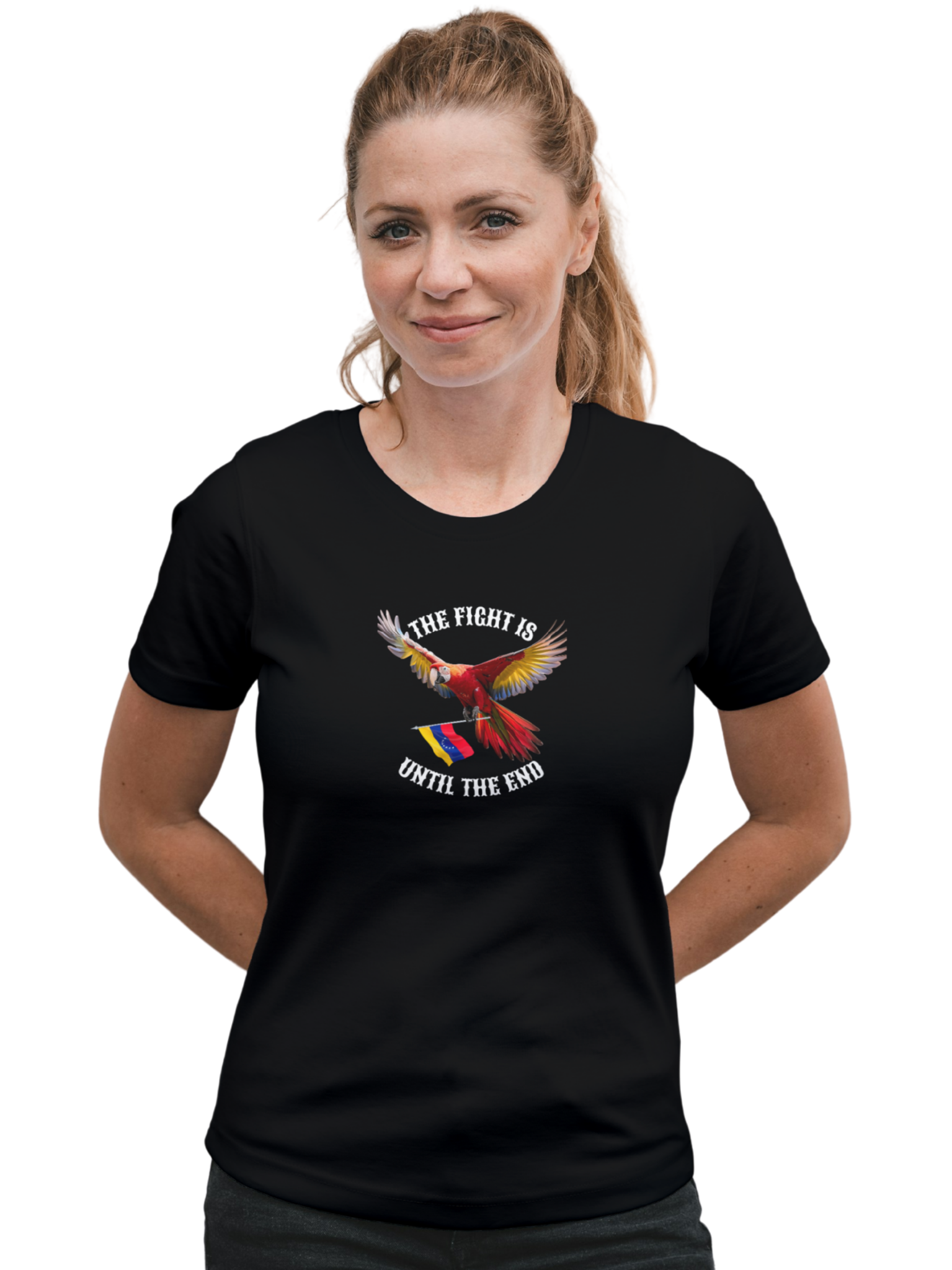 A smiling blonde woman wears a black T-shirt featuring an image of a macaw and the Venezuelan flag. The text "THE FIGHT IS UNTIL THE END" surrounds the bird.