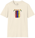 Franela color crema con la bandera venezolana de 7 estrellas, el nombre VENEZUELA arriba y una guacamaya a cada lado. Las palabras SERÁ y LIBRE se ubican verticalmente junto a la bandera.