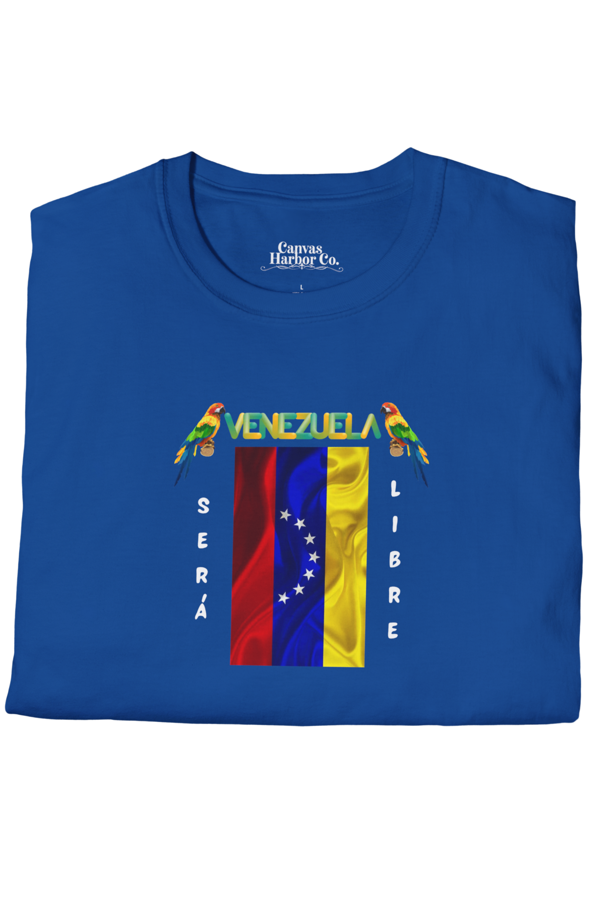 Franela azul doblada, con la bandera venezolana de 7 estrellas, el nombre VENEZUELA arriba y una guacamaya a cada lado. Las palabras SERÁ y LIBRE se ubican verticalmente junto a la bandera.