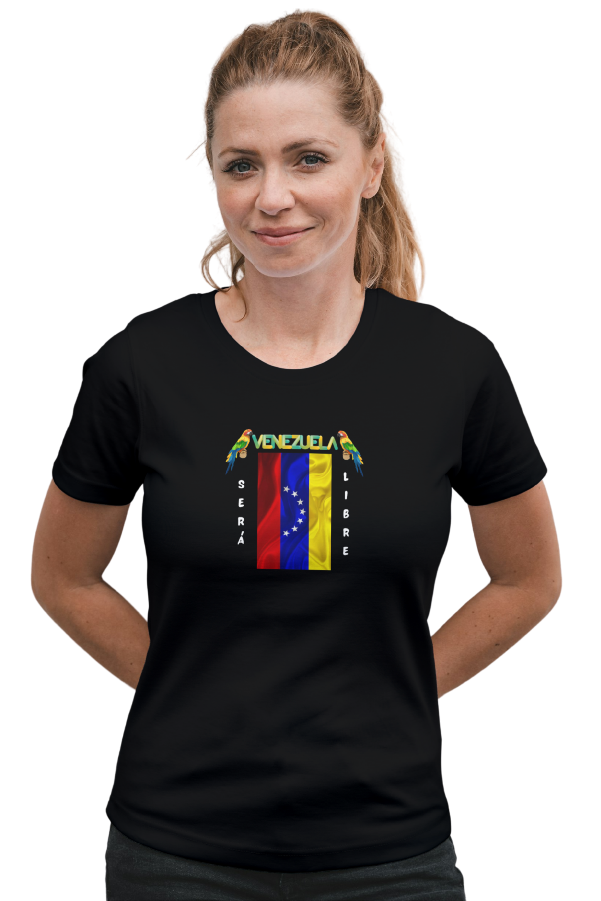 Una mujer joven viste una franela negra con la bandera venezolana de 7 estrellas, el nombre VENEZUELA arriba y una guacamaya a cada lado. Las palabras SERÁ y LIBRE se ubican verticalmente junto a la bandera.