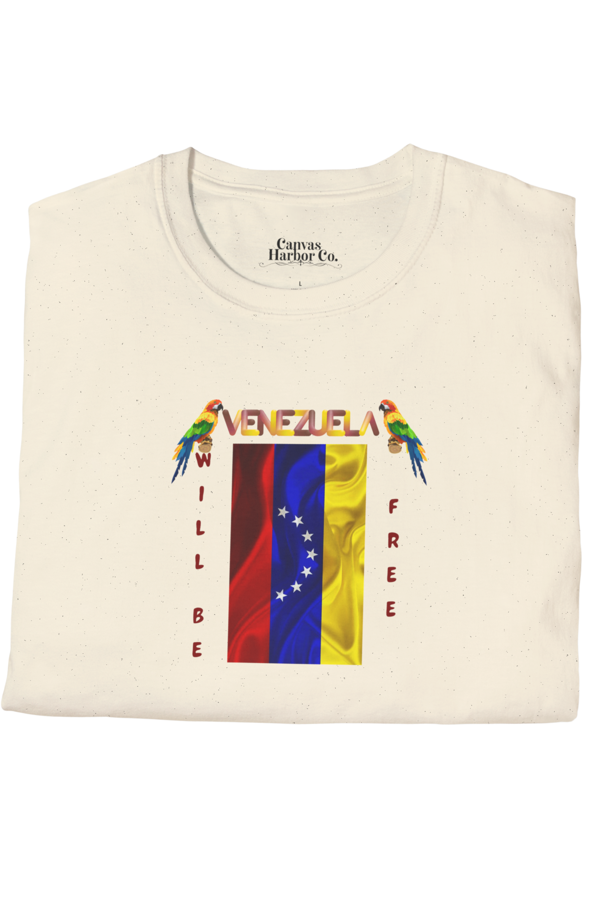 Pale orange folded T-shirt featuring the 7-star Venezuelan flag, the name VENEZUELA at the top, and one macaw on each side. The words WILL BE and FREE are all placed vertically next to the flag.
