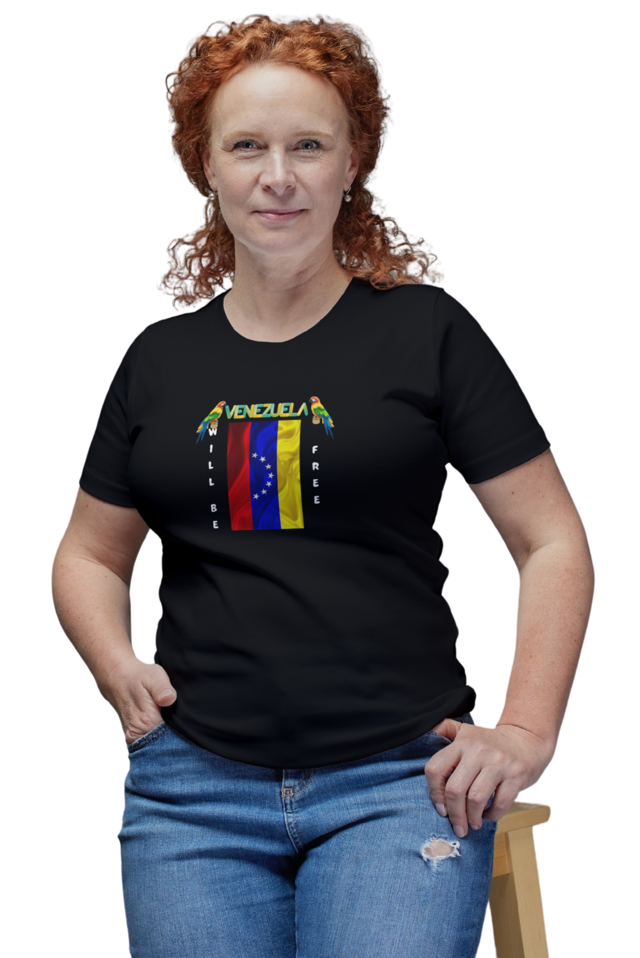 A red-haired woman wears a black T-shirt featuring the 7-star Venezuelan flag, the name VENEZUELA at the top, and one macaw on each side. The words WILL BE and FREE are all placed vertically next to the flag.