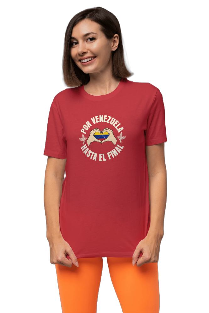 A smiling woman is wearing a red unisex t-shirt featuring a Venezuelan flag inside heart-shaped hands, the text "Por Venezuela Hasta El Final", and a pair of macaws on either side.