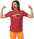 A woman is wearing a red unisex t-shirt featuring a heart-shaped Venezuelan flag, the word "Yo" on the left, and the text "¡Hasta El Final!" reading below. She is flexing her arms and smiling.