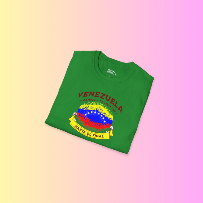 A folded green unisex t-shirt featuring a colorful, elliptically shaped Venezuelan flag dotted (like an explosion), with the text "Venezuela Camino a La Libertad" at the top and "Hasta El Final" on a yellow ribbon below the flag.