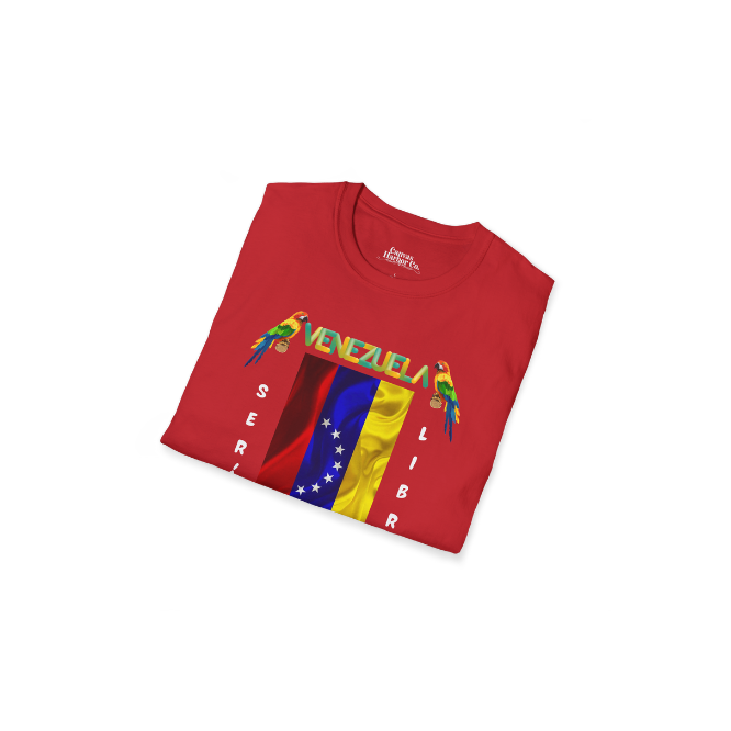 A folded red unisex t-shirt featuring a Venezuelan flag, the name "Venezuela" at the top, and a colorful macaw on either side. The text "Será Libre" is vertically positioned beside the flag.