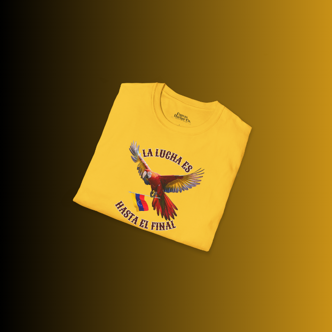 A folded yellow unisex t-shirt featuring a colorful macaw flying while holding the Venezuelan flag. The text "La Lucha Es" is at the top, and "Hasta El Final" is below the macaw. 