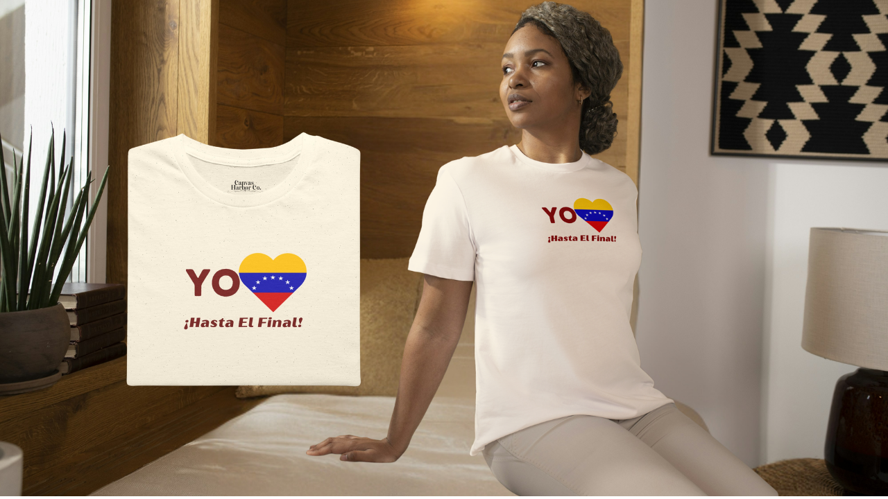 Franela color crema, doblada, con la bandera venezolana de 7 estrellas en forma de corazón, la palabra "YO" a la izquierda y el texto "¡HASTA EL FINAL!" debajo.
A la derecha, una mujer afroamericana viste la franela. Ella está en un cuarto, sentada sobre una cama. 