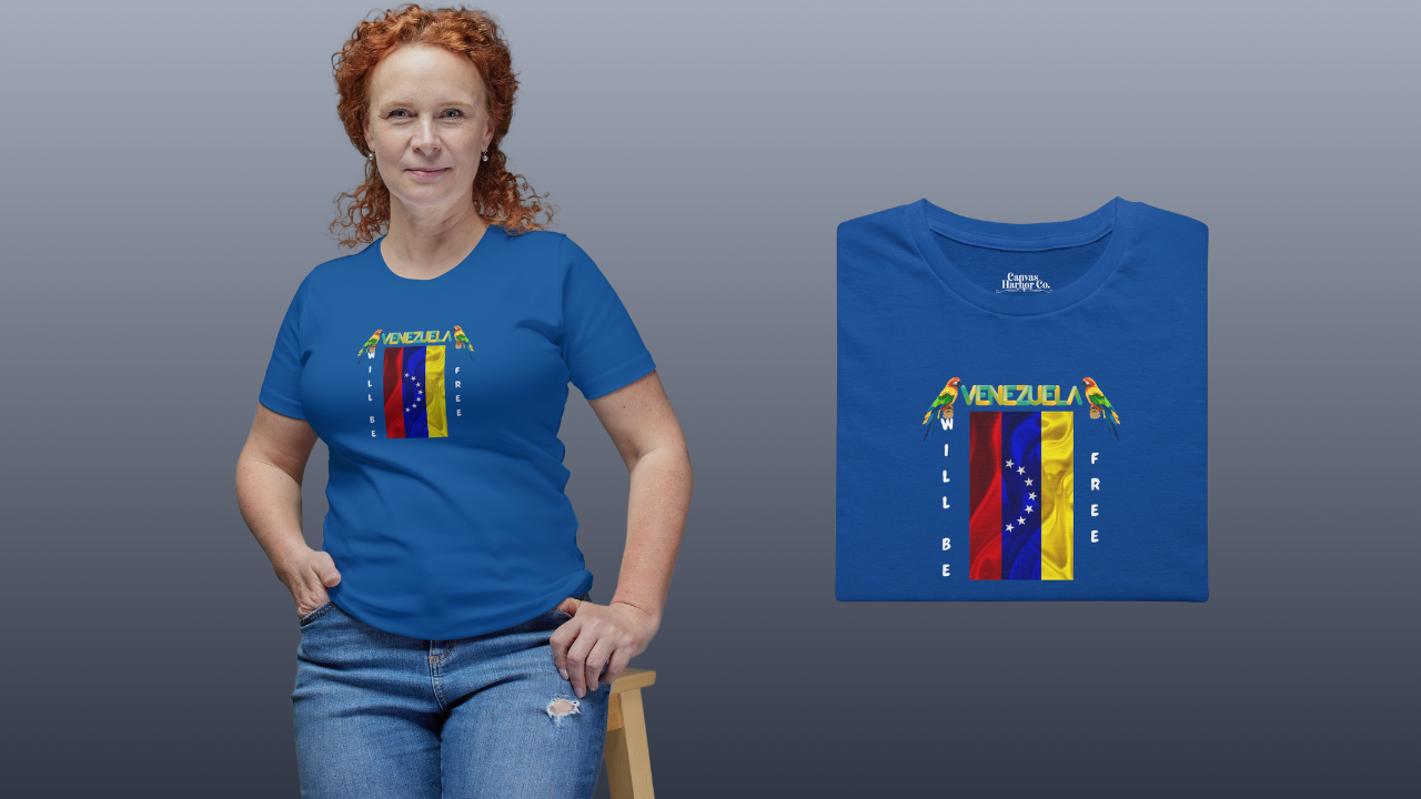 Blue folded T-shirt featuring the 7-star Venezuelan flag, the name VENEZUELA at the top, and one macaw on each side. The words WILL BE and FREE are all placed vertically next to the flag. 
On the left, a red-haired woman is wearing the T-shirt. She’s smiling, sitting on a small wooden bench. 