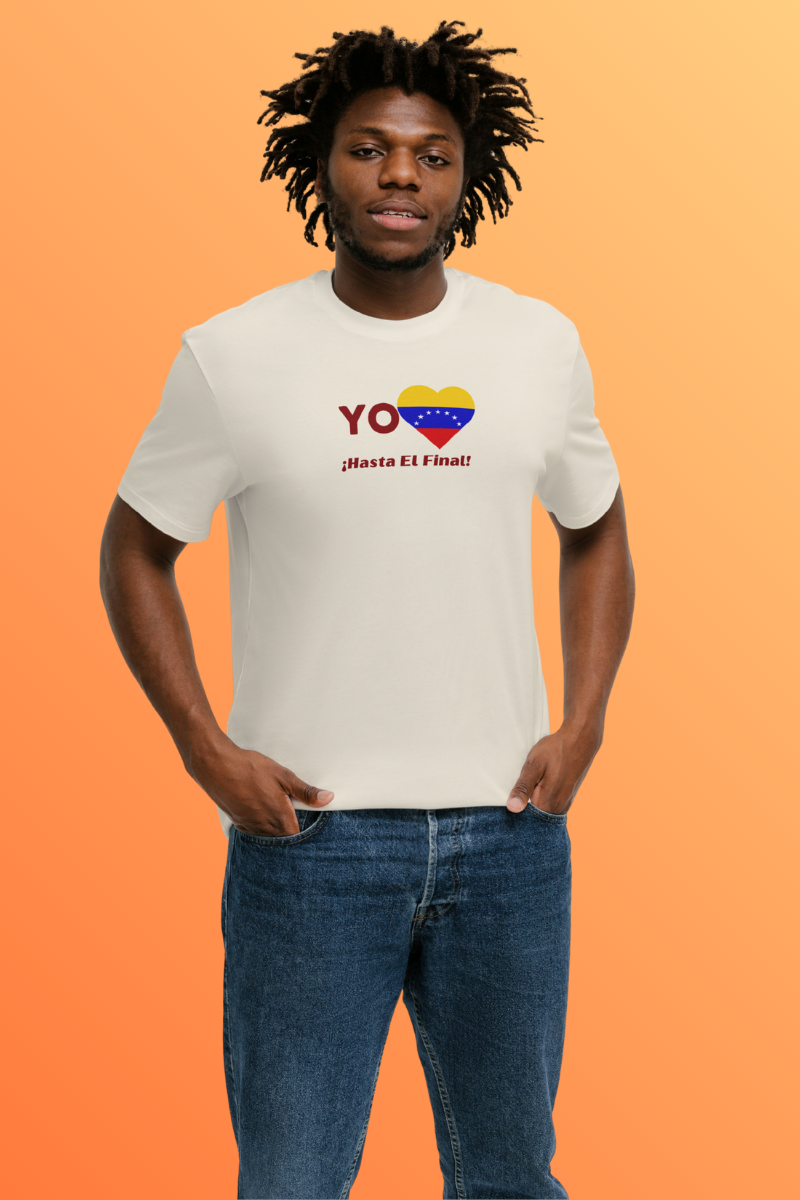 Un hombre afroamericano viste una franela color crema con la bandera venezolana de 7 estrellas en forma de corazón, la palabra "YO" a la izquierda y el texto "¡HASTA EL FINAL!" debajo.
Él está parado, mirando al frente. 