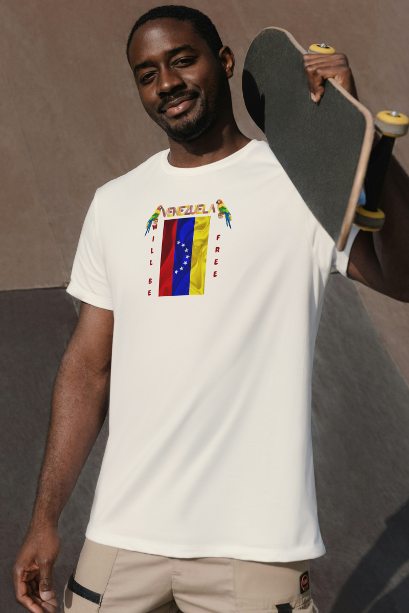 An Afro-American man is wearing a pale orange T-shirt featuring the 7-star Venezuelan flag, the name VENEZUELA at the top, and one macaw on each side. The words WILL BE and FREE are all placed vertically next to the flag. 
He’s standing, holding his skateboard over his left shoulder.