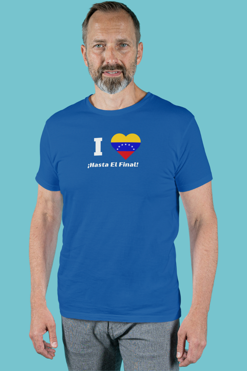 A man wears a blue T-shirt featuring the 7-star Venezuelan flag in the shape of a heart, the word "I" on the left, and the text "¡HASTA EL FINAL!" below.
He’s standing, facing forward.