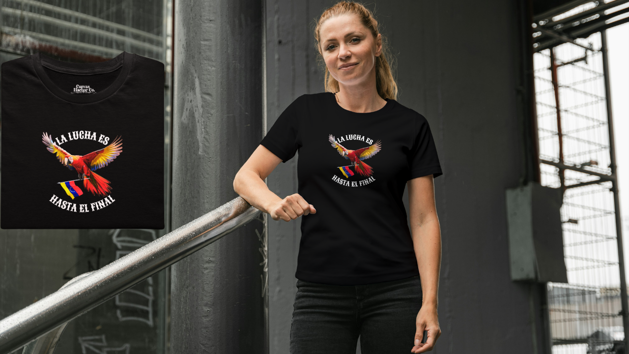 A la izquierda, hay una franela negra, doblada, con la imagen de un guacamayo con la bandera venezolana. La frase "LA LUCHA ES HASTA EL FINAL" rodea al ave.
En el medio de la foto, una mujer rubia viste la franela. Ella está parada, mirando al frente.