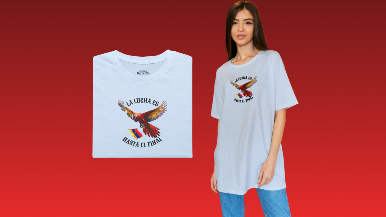 Franela azul claro, doblada, con la imagen de un guacamayo con la bandera venezolana. La frase "LA LUCHA ES HASTA EL FINAL" rodea al ave.
A la derecha, una mujer joven viste la franela. Ella está parada, mirando al frente.
