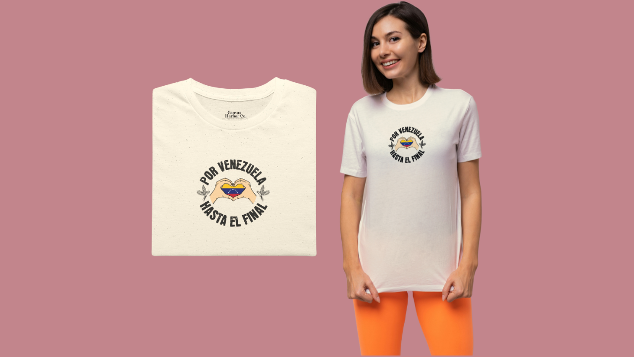 Franela color crema, doblada, con la bandera venezolana dentro de unas manos en forma de corazón, el texto "POR VENEZUELA HASTA EL FINAL" alrededor y una guacamaya a cada lado.
A la derecha, una mujer joven viste la franela. Ella sonríe, mirando al frente.