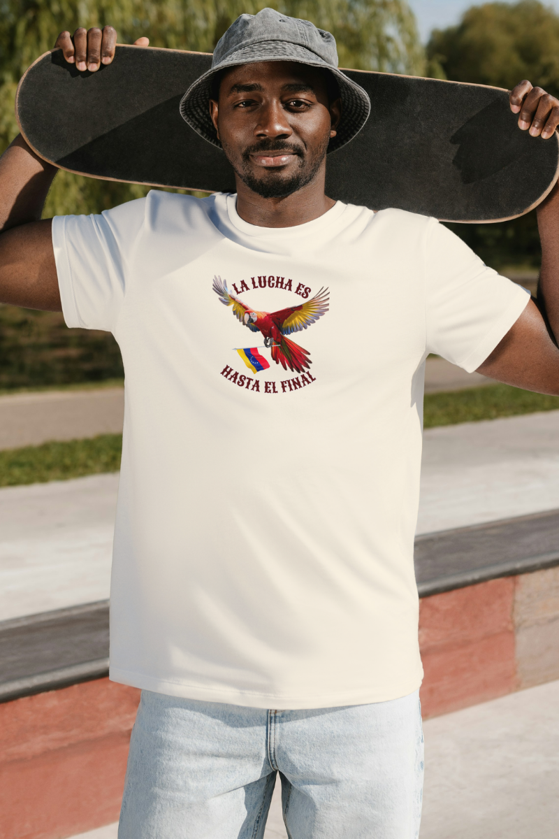 Un hombre afroamericano viste una franela color crema con la imagen de un guacamayo con la bandera venezolana. La frase "LA LUCHA ES HASTA EL FINAL" rodea al ave.
Él está de pie, sosteniendo su patineta por detrás de su cabeza.