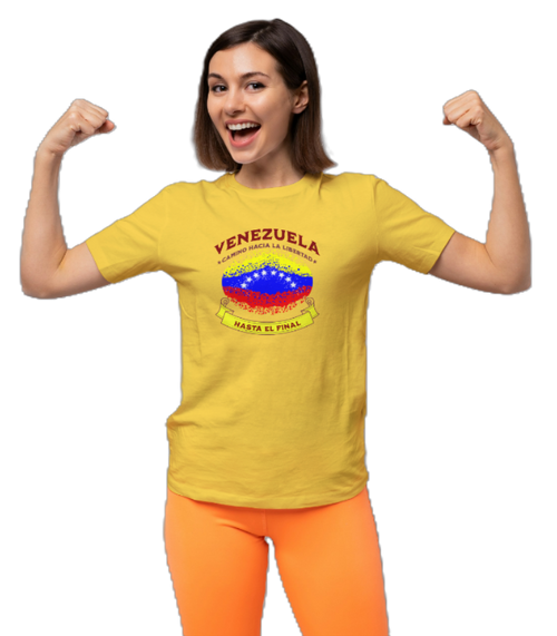 A woman is wearing a yellow unisex t-shirt featuring a colorful, elliptically shaped Venezuelan flag dotted (like an explosion), with the text "Venezuela Camino Hacia La Libertad" at the top and "Hasta El Final" on a yellow ribbon below the flag.